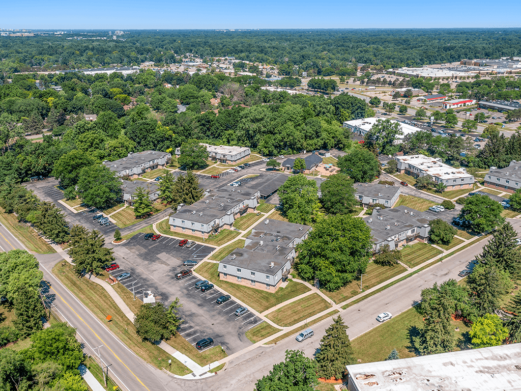 A bird's eye view of a parking lot surrounded by buildings and trees.
