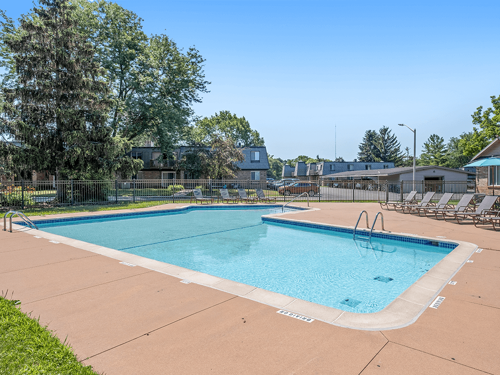 A large outdoor swimming pool surrounded by trees and lounge chairs.