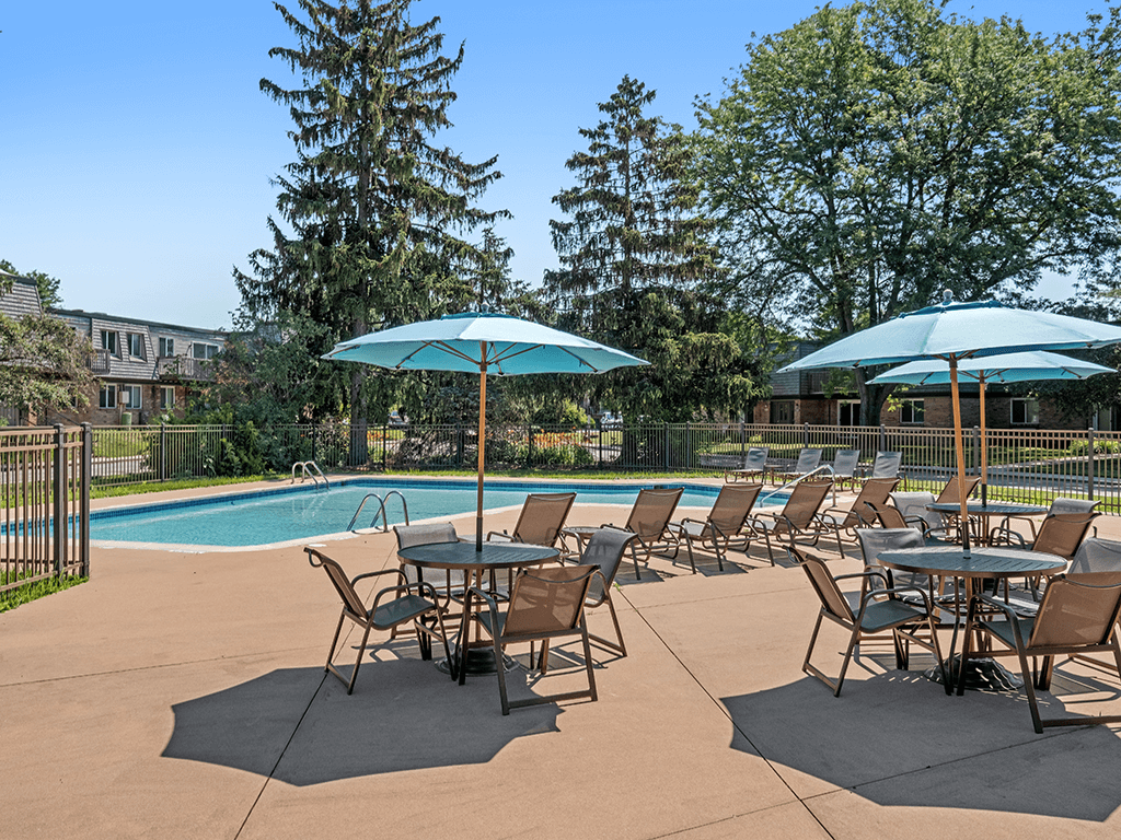 A poolside table set up with chairs and umbrellas.