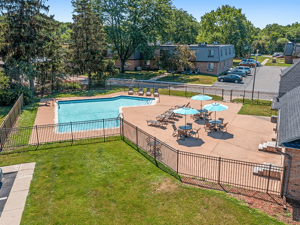A pool surrounded by a fence and chairs.
