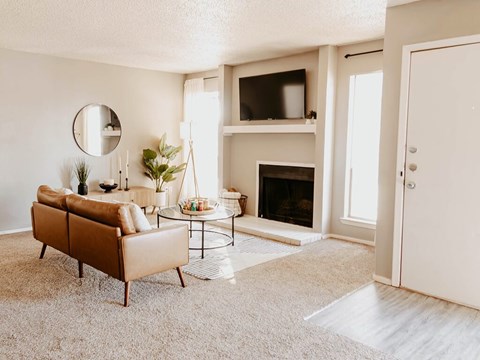 A living room with a brown sofa, a fireplace, and a mirror on the wall.