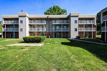 an apartment building with a green yard in front of it