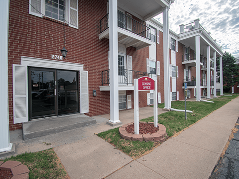 A red sign that says Leasing Office stands in front of a brick building.