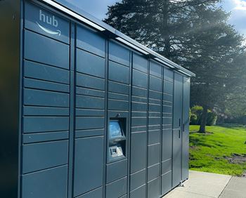 a large blue storage shed with an open door and a newspaper dispenser on the side