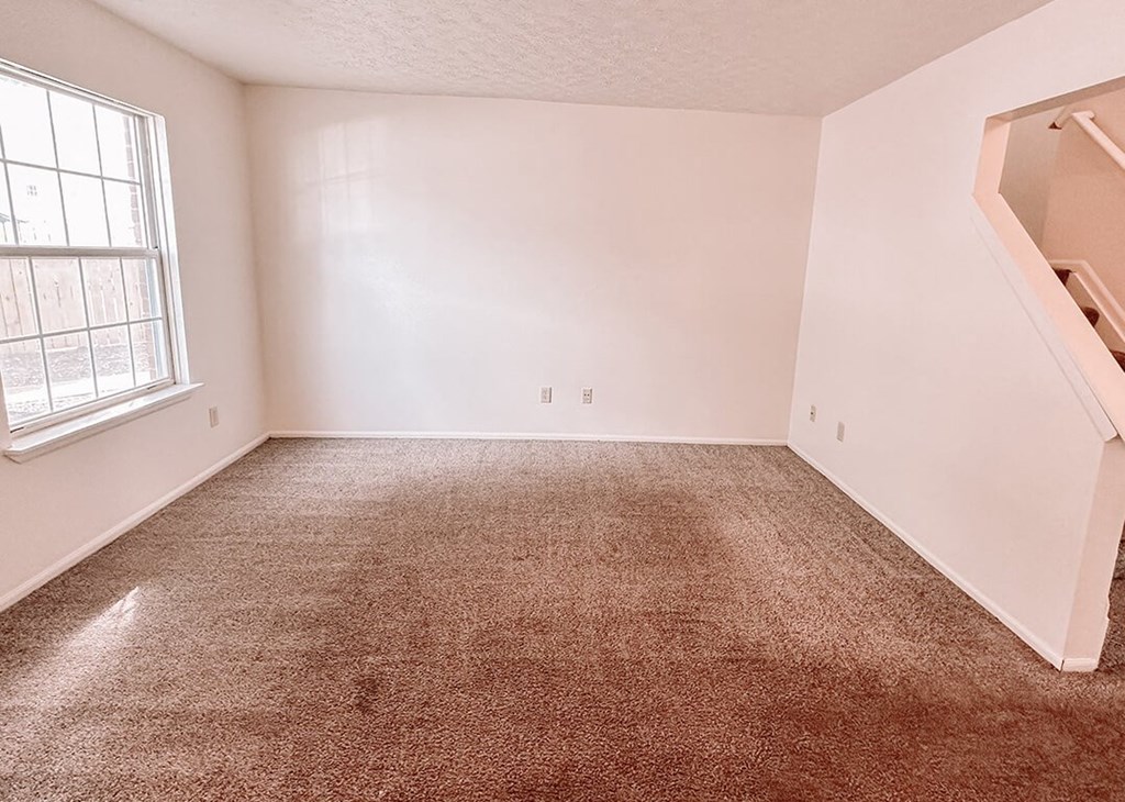 an empty room with a carpeted floor and a window