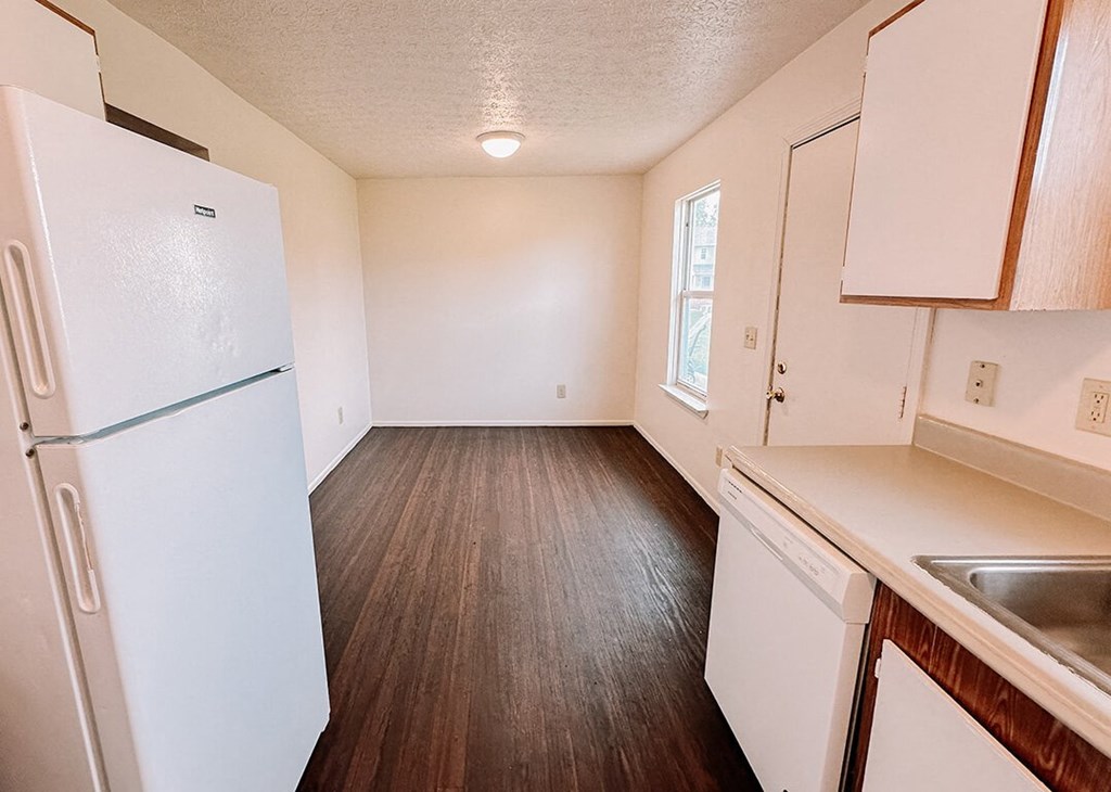 an empty kitchen with a refrigerator and a sink