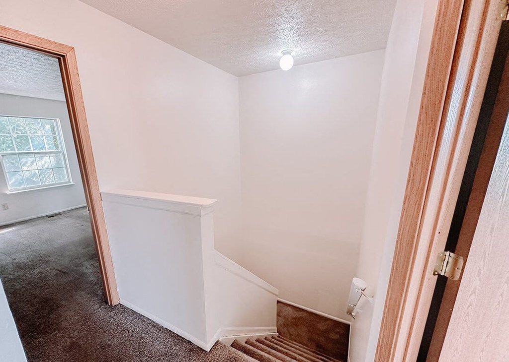 a doorway into a room with a staircase and a window