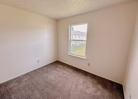 an empty room with a window and carpet