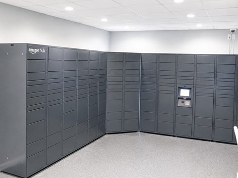 A row of Amazon locker units are lined up in a room.