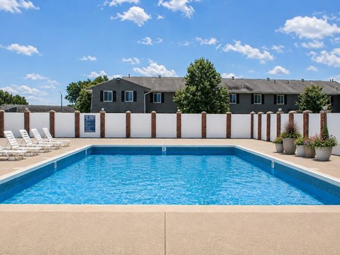 A swimming pool surrounded by a white fence and chairs.