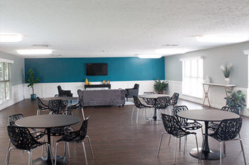 a room with tables and chairs and a couch in the background