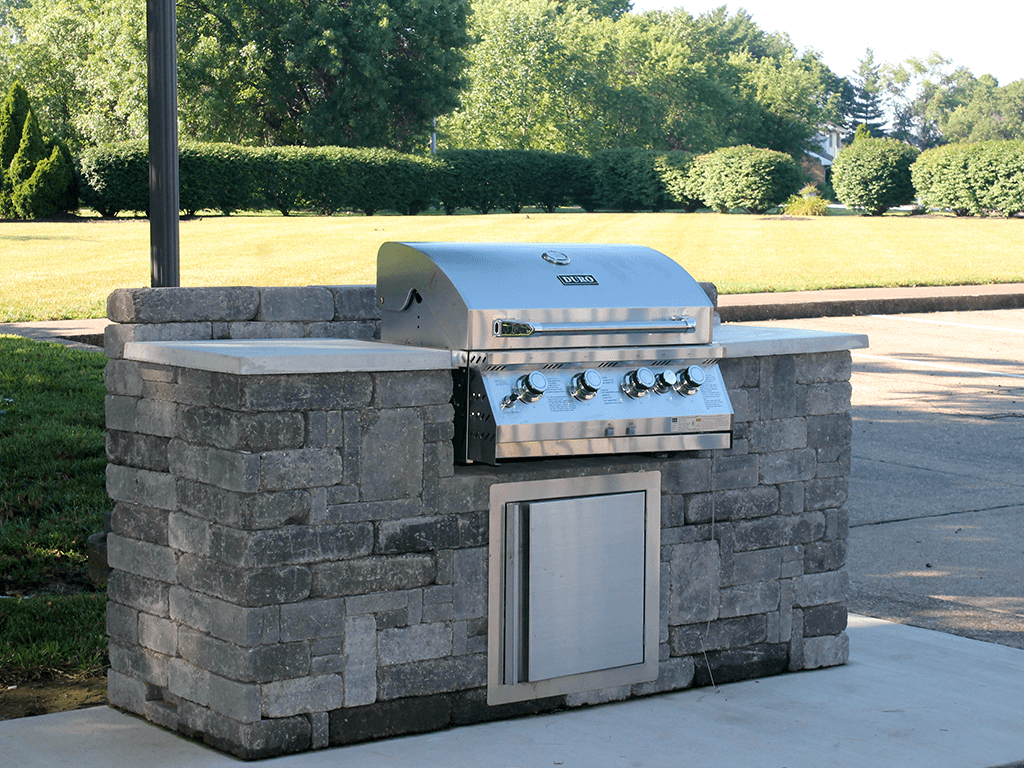 a stone outdoor kitchen with a grill in a park