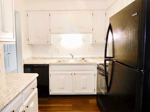 a kitchen with white cabinets and a black refrigerator
