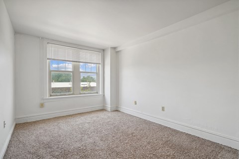 A room with a carpeted floor and a window.