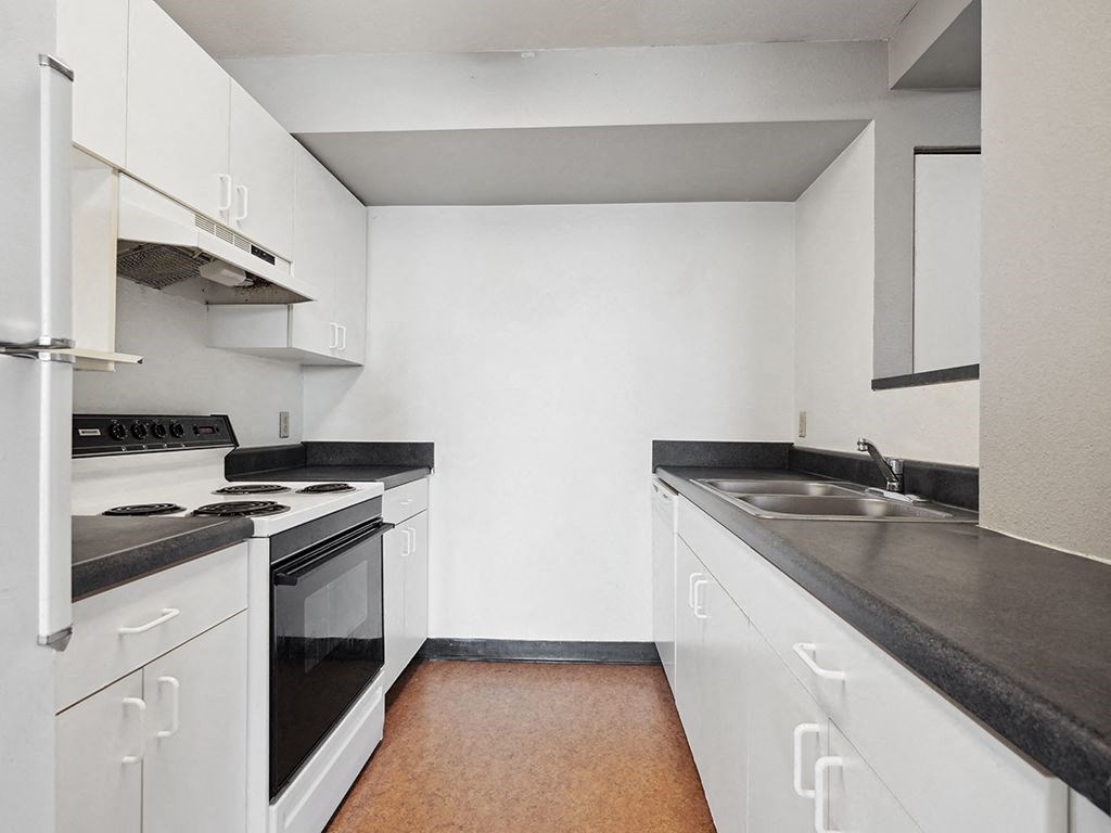 a kitchen with white cabinets and black counter tops