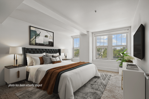 A bedroom with a large bed and a flat screen TV mounted on the wall.