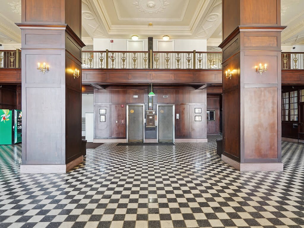the lobby of a building with pillars and a checkered floor