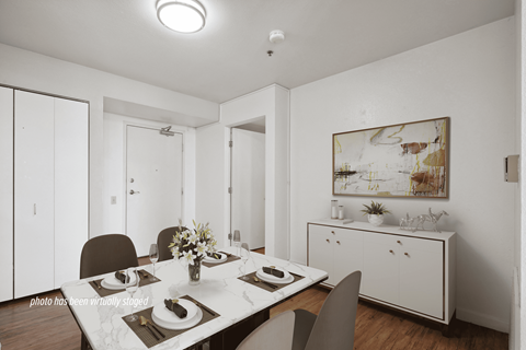 A dining room with a table set for two and a painting on the wall.