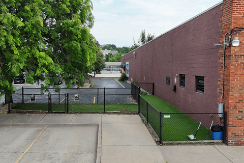 A red brick building with a black fence and a green lawn in front.