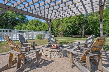 a patio with wooden chairs and a fire pit