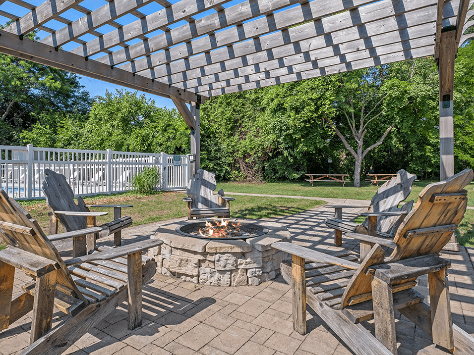 a patio with wooden chairs and a fire pit