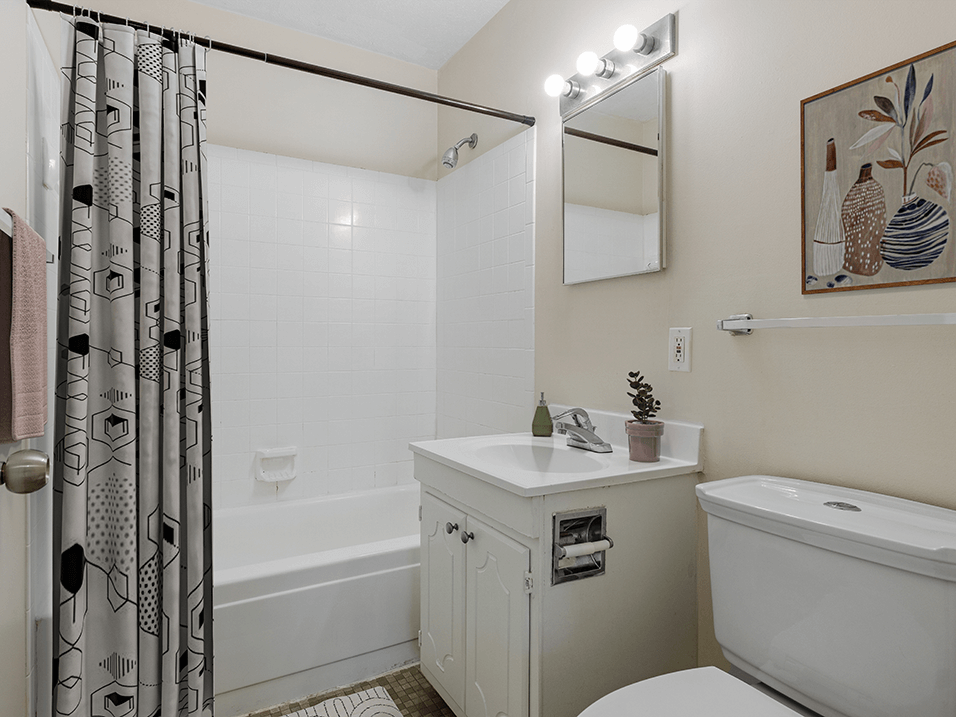 a bathroom with white fixtures and a black and white shower curtain
