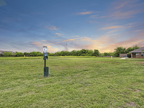 A signpost stands in a grassy field with a building in the background.