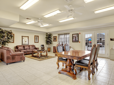 A living room with a brown leather couch, a wooden table, and a ceiling fan.