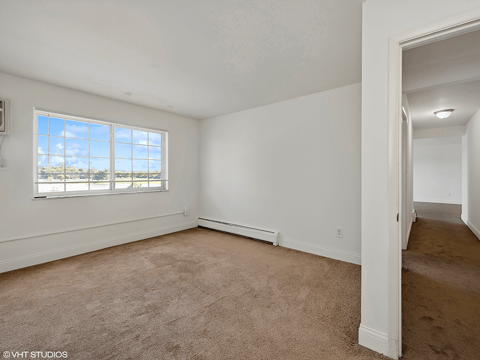 an empty living room with carpet and a window