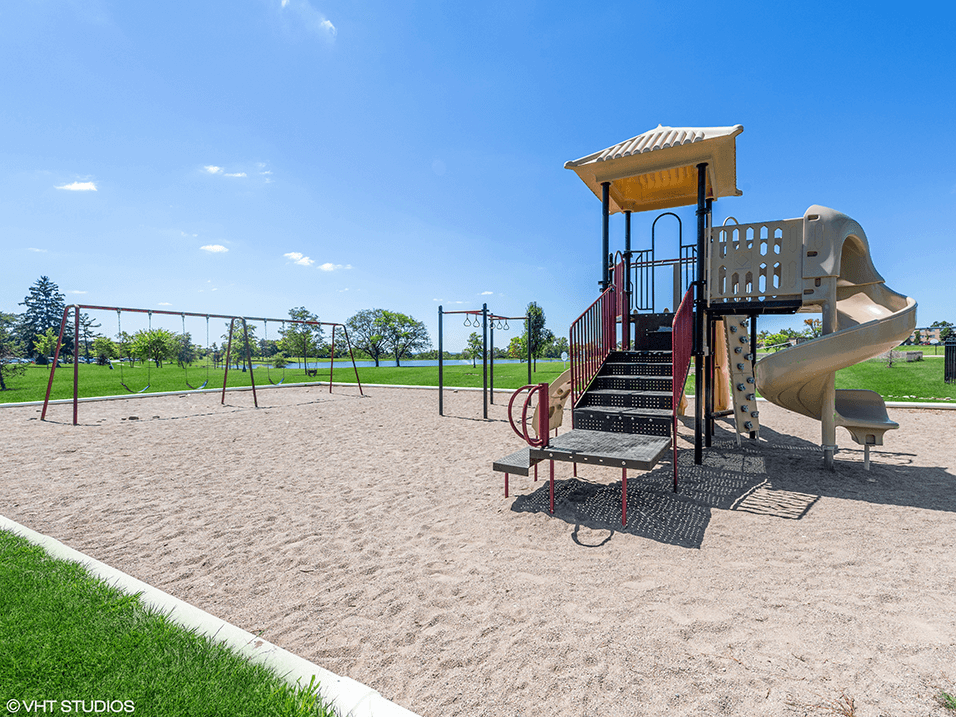 a playground with a swing set and a slide at an apartment complex