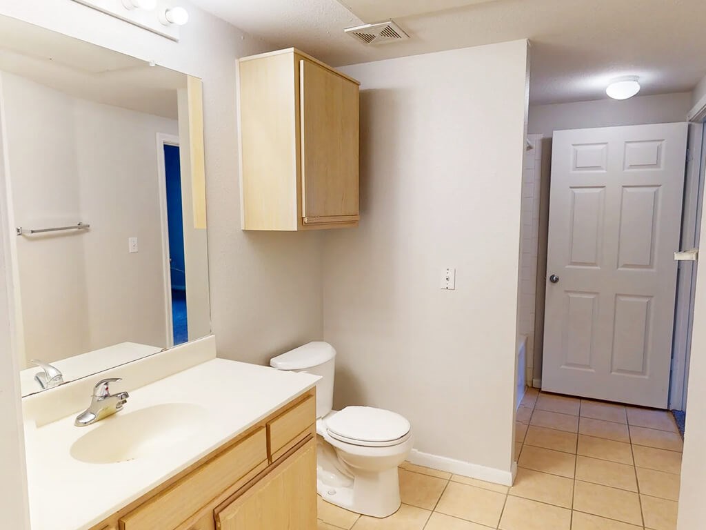 A bathroom with a toilet, sink, and medicine cabinet.