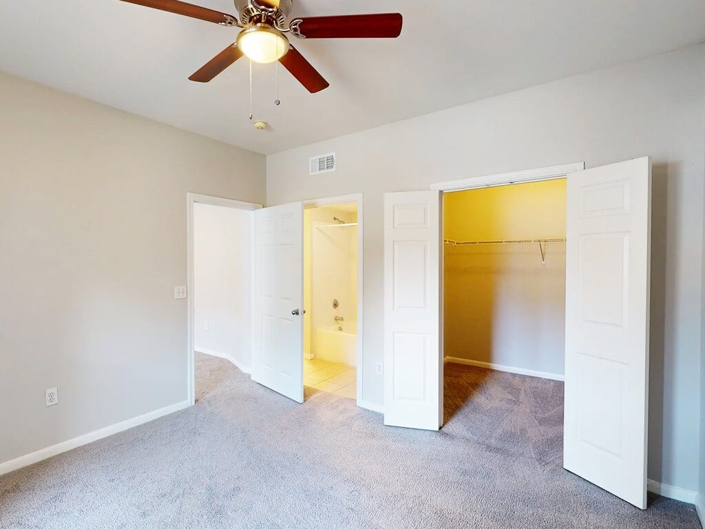 A room with a ceiling fan and carpeted floor.