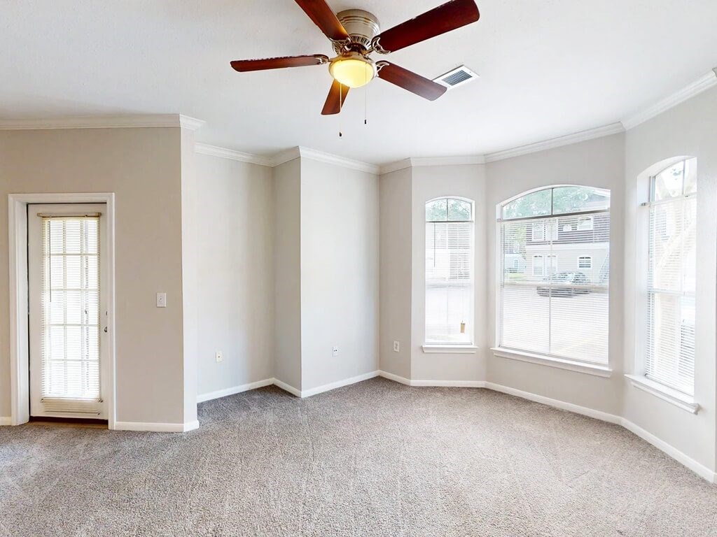 A room with a ceiling fan and carpeted floor.