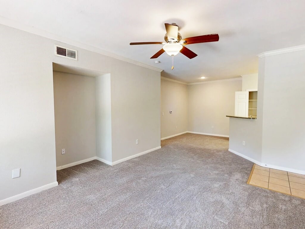 A room with a ceiling fan and carpeted floor.