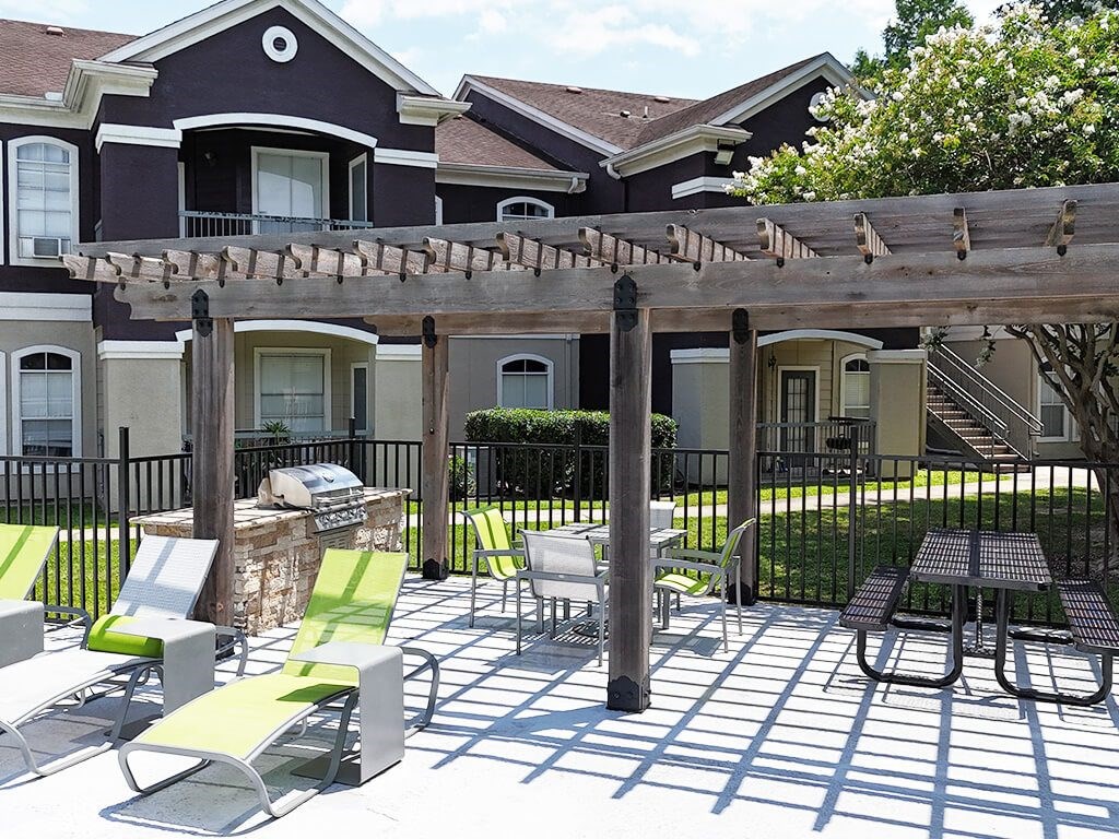 A patio with a table and chairs is in front of a house.