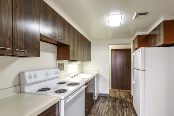 A kitchen with white appliances and wooden cabinets.