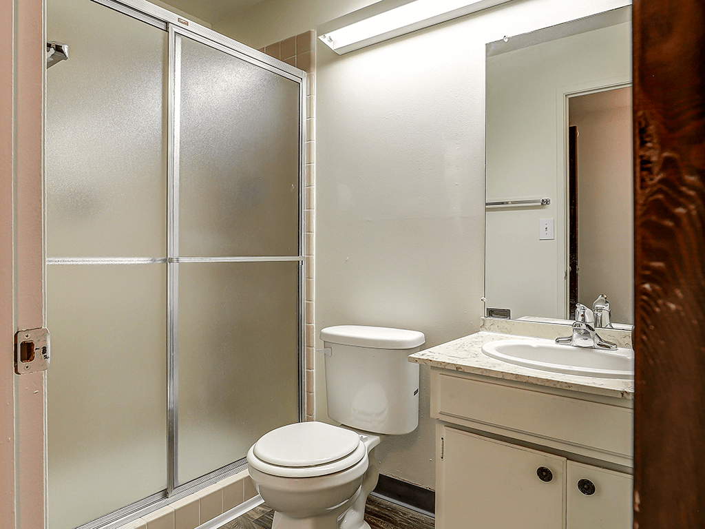 A white toilet sits in a bathroom next to a sink.