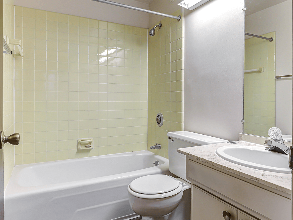 A white toilet sits next to a bathtub in a bathroom.