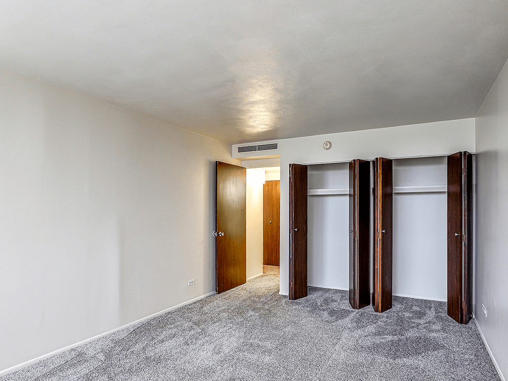 A room with a carpeted floor and a white ceiling with three doors.