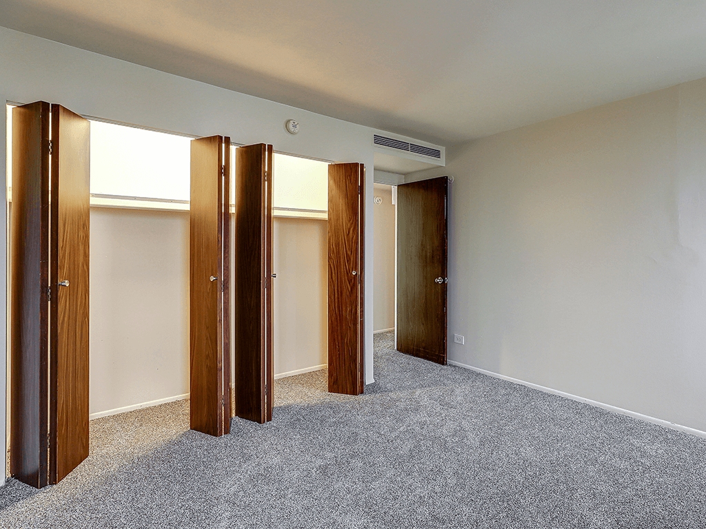 A room with a carpeted floor and four wooden doors.