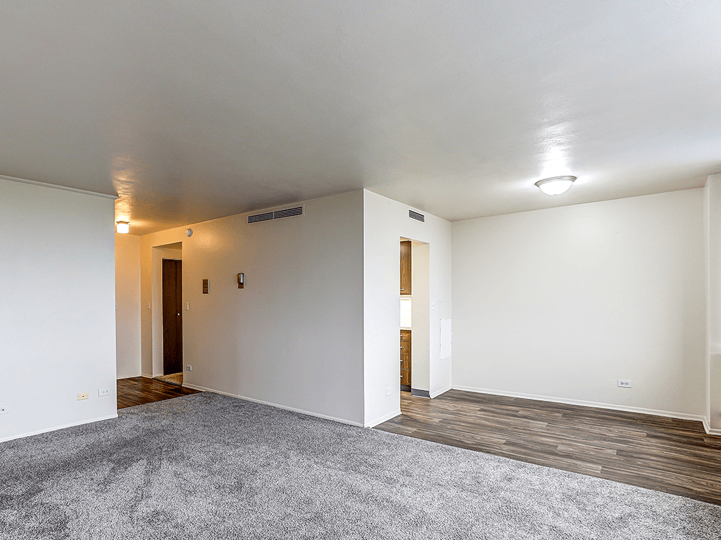 A room with a grey carpet and wooden floors.