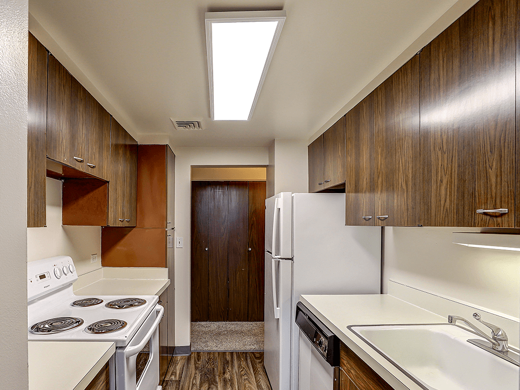 A kitchen with white appliances and wooden cabinets.