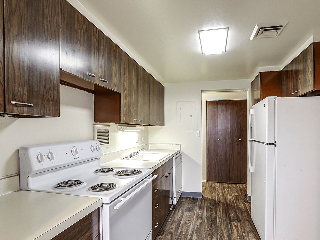 A kitchen with white appliances and wood cabinets.