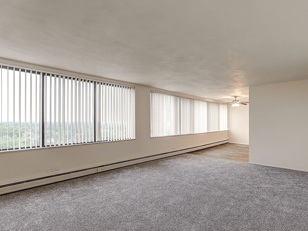 A room with a carpeted floor and a window with blinds.
