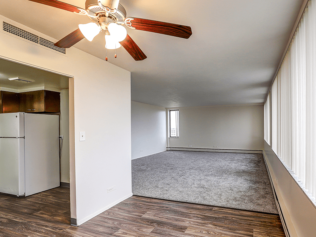 A room with a ceiling fan and a refrigerator.