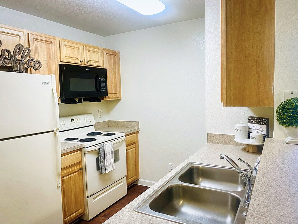 A kitchen with a white refrigerator, a black microwave, and a white oven.