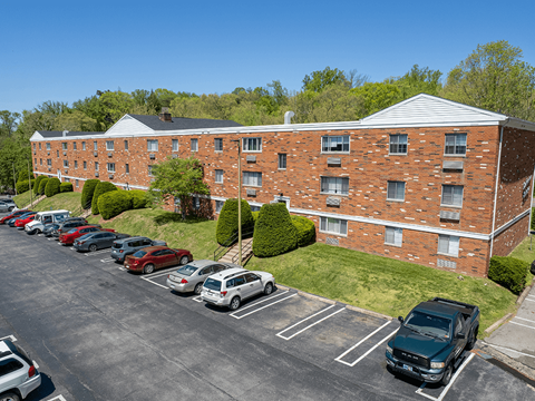 A parking lot with cars parked in front of a red brick building.