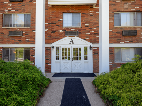 A brick building with a white door and a black mat in front.