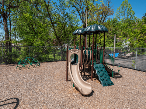 A playground with a brown slide and a green canopy.