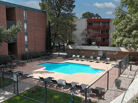 A pool surrounded by chairs and a fence.
